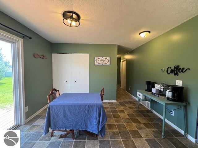 2195 S Sara Dr, Lake City, MI 49651 - dining room featuring a textured ceiling, baseboards, and stone finish floors