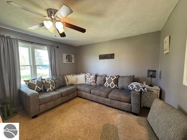2195 S Sara Dr, Lake City, MI 49651 - living area featuring ceiling fan, a textured ceiling, and light colored carpet