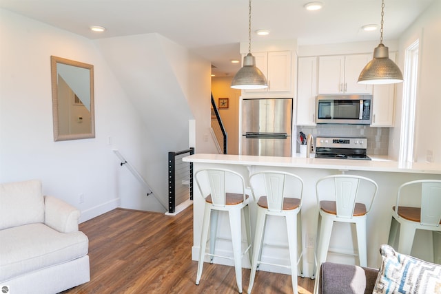 kitchen featuring stainless steel appliances, hanging light fixtures, a kitchen bar, and recessed lighting