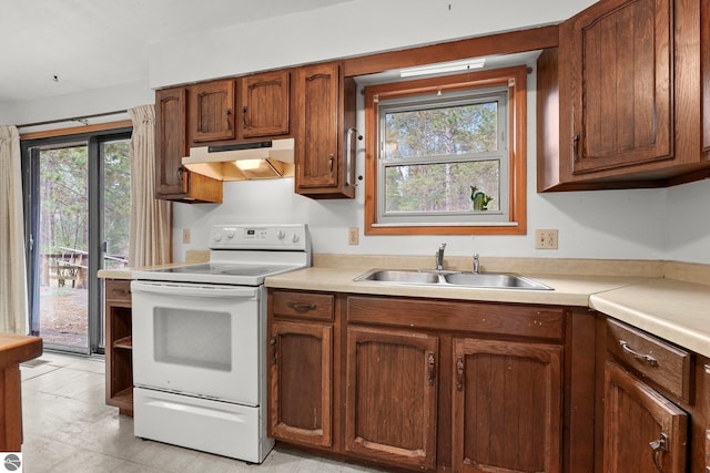 kitchen with under cabinet range hood, electric range, a sink, light countertops, and brown cabinets