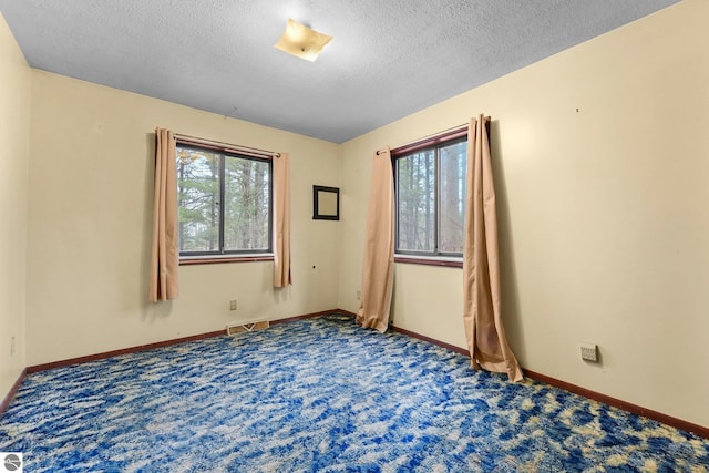 unfurnished room featuring carpet floors, a textured ceiling, and baseboards