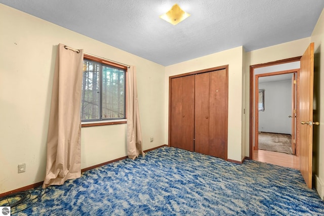 unfurnished bedroom with carpet flooring, baseboards, a textured ceiling, and a closet