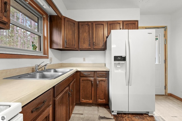 kitchen with white fridge with ice dispenser, a sink, light countertops, and stove