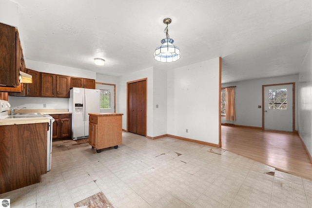 kitchen featuring white fridge with ice dispenser, light floors, a center island, light countertops, and range hood