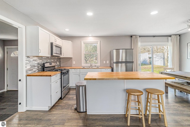 4507 Maidens Rd, Onekama, MI 49675 - kitchen with wood counters, appliances with stainless steel finishes, white cabinetry, plenty of natural light, and recessed lighting