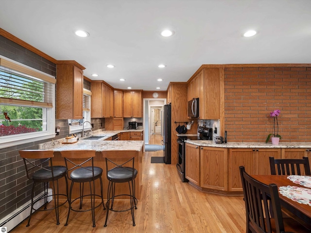 9311 Whipple Shores Dr, Clarkston, MI 48348 - kitchen with stainless steel appliances, a sink, a baseboard heating unit, a peninsula, and light stone countertops
