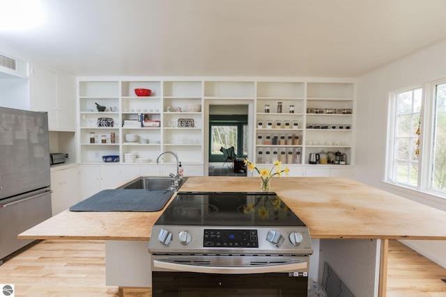 3080 N Lake Leelanau Dr, Lake Leelanau, MI 49653 - kitchen featuring stainless steel appliances, open shelves, a sink, light wood-style flooring, and plenty of natural light