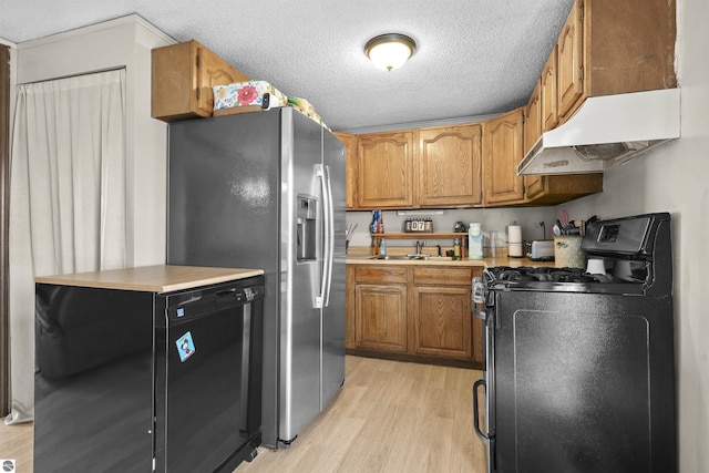 3610 S Call Rd, Lake City, MI 49651 - kitchen featuring range with gas cooktop, under cabinet range hood, fridge, light wood-style floors, and brown cabinets