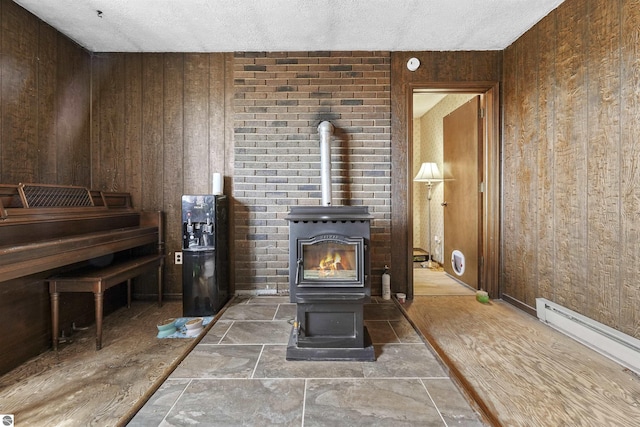 3610 S Call Rd, Lake City, MI 49651 - living area with a wood stove, wooden walls, a baseboard radiator, and a textured ceiling