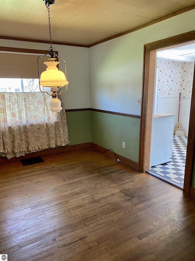 unfurnished dining area featuring hardwood / wood-style floors, ornamental molding, and baseboards