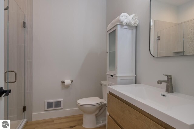 127 River St, Elk Rapids, MI 49629 - full bathroom with a stall shower, toilet, wood finished floors, vanity, and baseboards