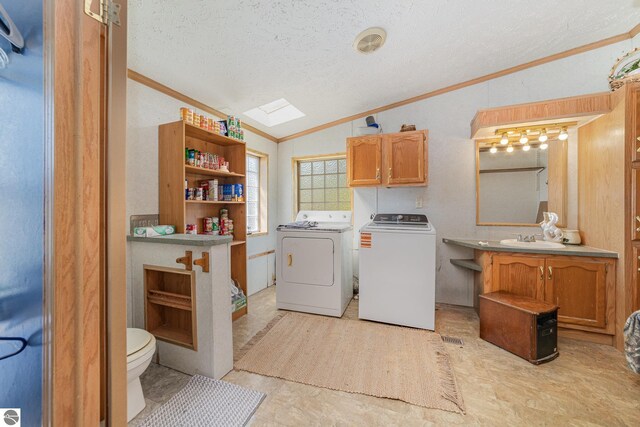 10946 N Rich Rd, Alma, MI 48801 - laundry room featuring washer and dryer, crown molding, a skylight, a textured ceiling, and light flooring