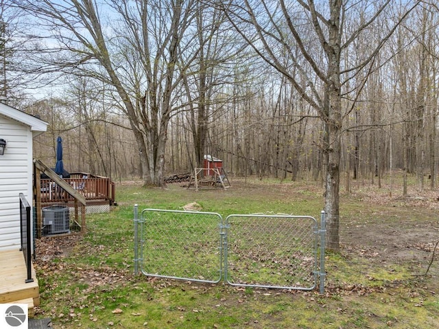 11420 Muskie Way, Ellsworth, MI 49729 - view of yard with a gate, central air condition unit, a deck, and a forest view