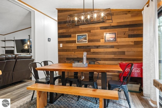 11420 Muskie Way, Ellsworth, MI 49729 - dining space with wood finished floors, a chandelier, vaulted ceiling, wooden walls, and ornamental molding