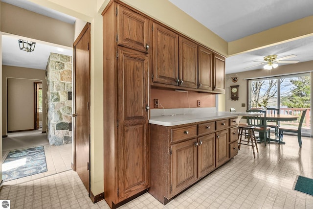 11531 S Tower Rd, Maple City, MI 49664 - kitchen with light countertops, a ceiling fan, brown cabinetry, and light tile patterned floors