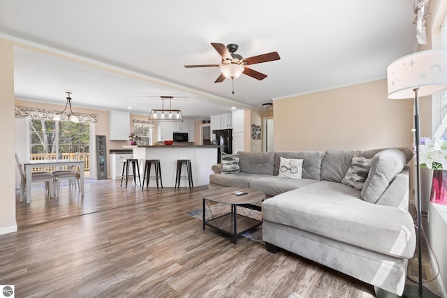 714 SE Saunders Rd, Kalkaska, MI 49646 - living room with wood finished floors, ceiling fan, and ornamental molding