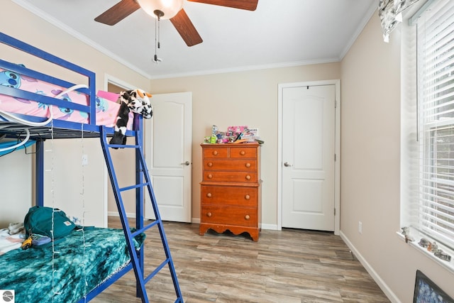 714 SE Saunders Rd, Kalkaska, MI 49646 - bedroom featuring light wood finished floors, multiple windows, ornamental molding, a ceiling fan, and baseboards