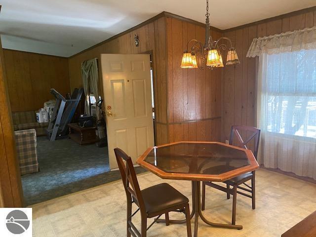8067 Cherry Ave, Rapid City, MI 49676 - dining room with wooden walls, light floors, and a chandelier