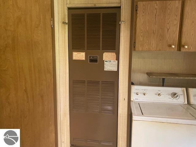 8067 Cherry Ave, Rapid City, MI 49676 - washroom featuring washer / clothes dryer, a heating unit, and cabinet space