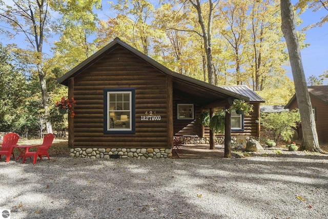 421 S Shabwasung St, Northport, MI 49670 - cabin with log siding, covered porch, a standing seam roof, and metal roof