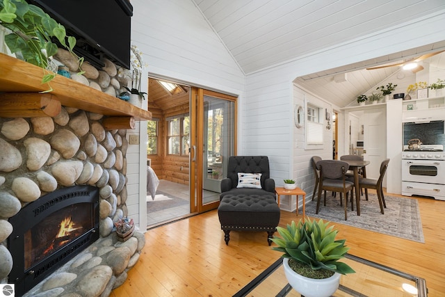 421 S Shabwasung St, Northport, MI 49670 - living area with light wood finished floors, a stone fireplace, wood ceiling, high vaulted ceiling, and wooden walls