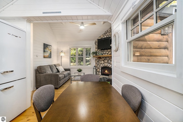 421 S Shabwasung St, Northport, MI 49670 - dining space featuring light wood-style floors, a stone fireplace, wood ceiling, and wooden walls