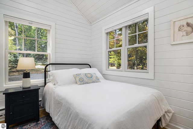 421 S Shabwasung St, Northport, MI 49670 - bedroom featuring wood walls, multiple windows, and vaulted ceiling