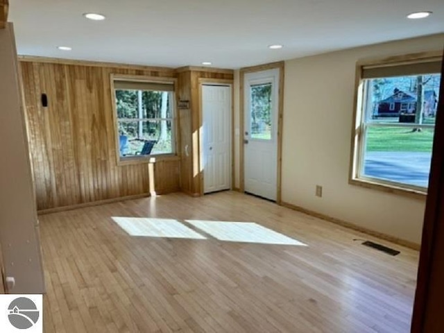 unfurnished living room with wood finished floors, baseboards, wood walls, and recessed lighting