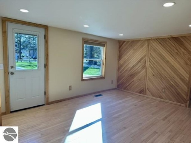foyer entrance featuring light wood-style floors, baseboards, wood walls, and recessed lighting