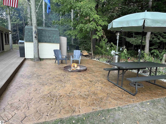 view of patio / terrace featuring a fire pit, a shed, and an outbuilding