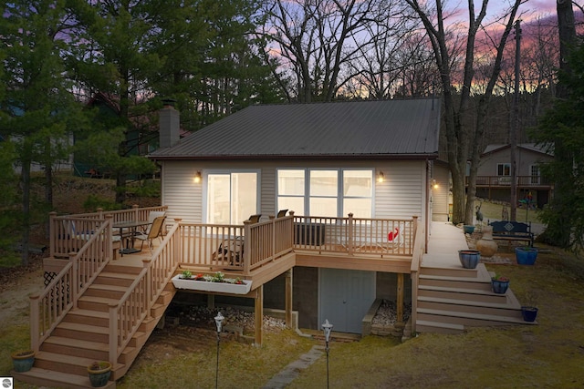 1750 S Schneider St, Lake City, MI 49651 - back of house at dusk with stairway, metal roof, a wooden deck, and a chimney
