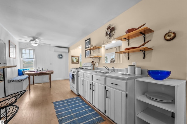 1750 S Schneider St, Lake City, MI 49651 - kitchen featuring open shelves, white range with gas cooktop, a sink, a wall unit AC, and light wood-style flooring
