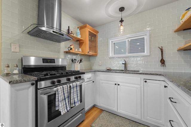 1750 S Schneider St, Lake City, MI 49651 - kitchen featuring stainless steel range with gas stovetop, open shelves, wall chimney exhaust hood, a sink, and decorative backsplash
