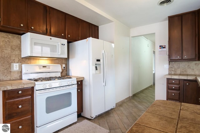 12225 SW Torch Lake Dr SW, Rapid City, MI 49676 - kitchen with white appliances, decorative backsplash, dark brown cabinets, wood finished floors, and baseboards
