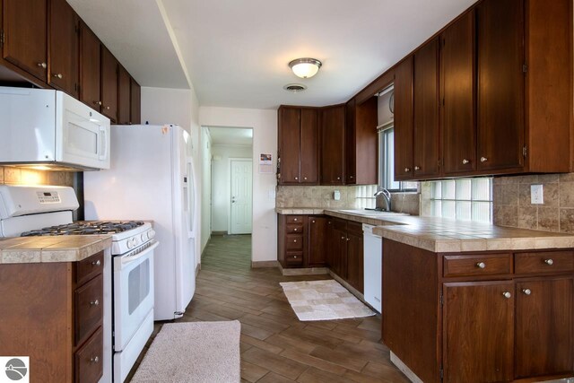 12225 SW Torch Lake Dr SW, Rapid City, MI 49676 - kitchen with white appliances, dark wood-type flooring, tasteful backsplash, a sink, and baseboards