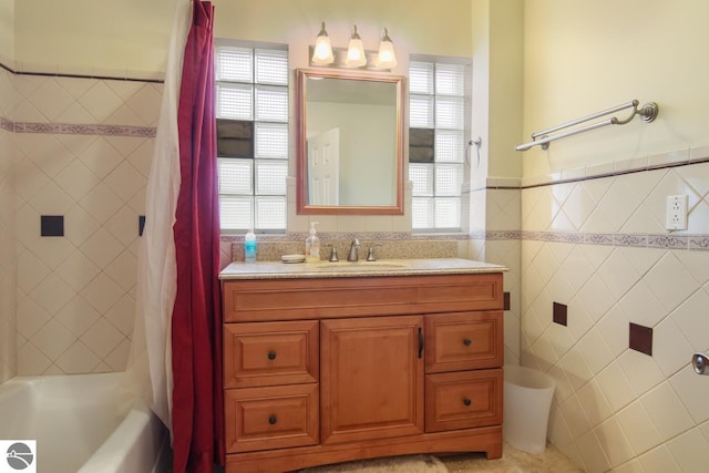 12225 SW Torch Lake Dr SW, Rapid City, MI 49676 - bathroom featuring tile walls, healthy amount of natural light, vanity, shower / tub combo with curtain, and wainscoting