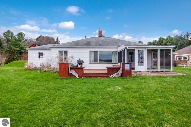 12225 SW Torch Lake Dr SW, Rapid City, MI 49676 - back of property with a wooden deck, a sunroom, a chimney, and a yard