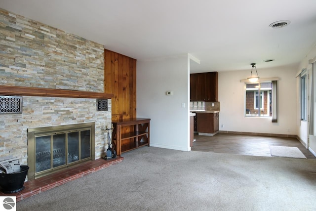 12225 SW Torch Lake Dr SW, Rapid City, MI 49676 - unfurnished living room featuring carpet flooring, baseboards, and a stone fireplace