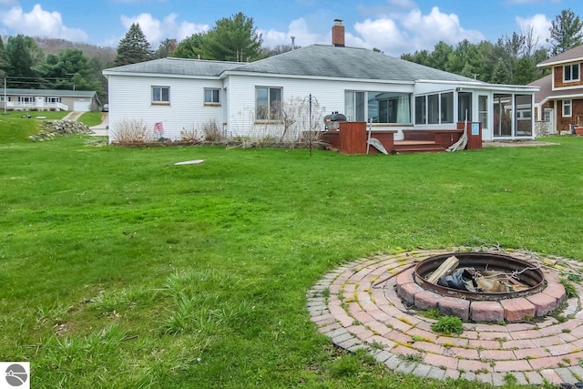 12225 SW Torch Lake Dr SW, Rapid City, MI 49676 - back of house with an outdoor fire pit, a sunroom, a yard, a chimney, and a shingled roof