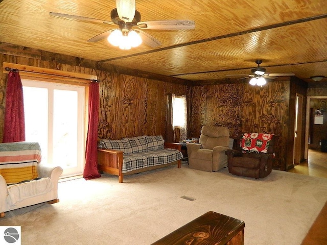 living area featuring wooden ceiling, a ceiling fan, wooden walls, and carpet