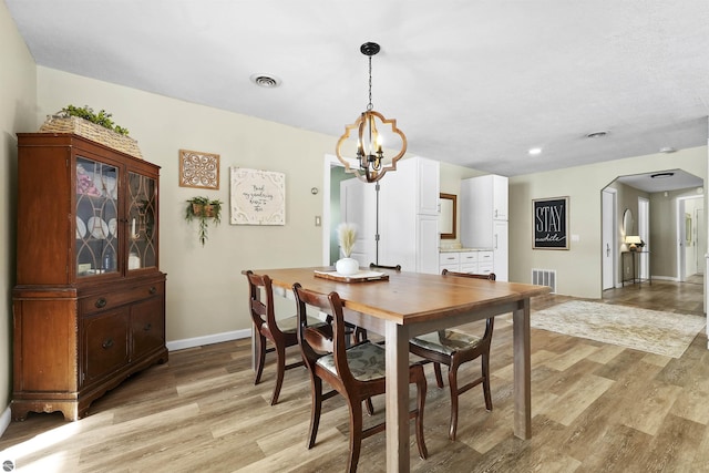 8481 E Houghton Lake Rd, Merritt, MI 49667 - dining area with light wood-style flooring, arched walkways, baseboards, and a chandelier