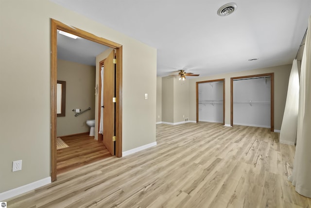 8481 E Houghton Lake Rd, Merritt, MI 49667 - unfurnished bedroom featuring two closets, light wood-style floors, baseboards, and connected bathroom