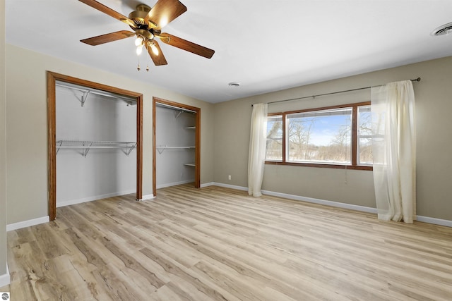 8481 E Houghton Lake Rd, Merritt, MI 49667 - unfurnished bedroom featuring multiple closets, light wood-type flooring, baseboards, and a ceiling fan