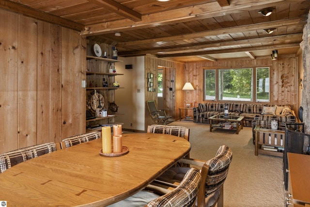 carpeted dining area with wood walls, beamed ceiling, and wooden ceiling