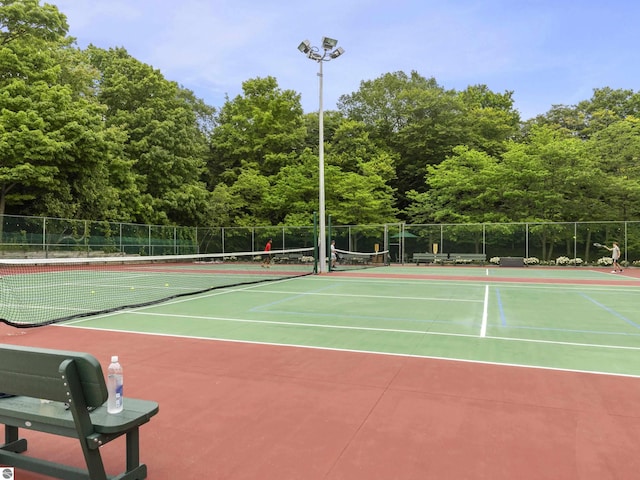 view of tennis court featuring fence and community basketball court
