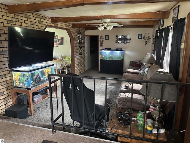 carpeted living area featuring brick wall, beam ceiling, a ceiling fan, and arched walkways