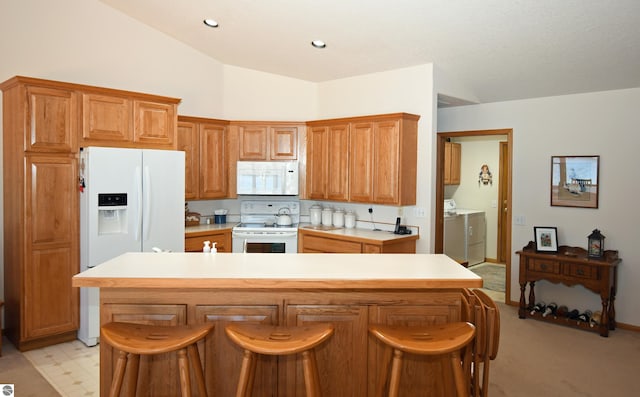 kitchen featuring white appliances, separate washer and dryer, light countertops, vaulted ceiling, and a kitchen island