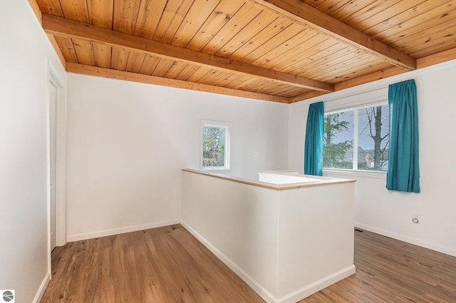 corridor with an upstairs landing, beamed ceiling, wood finished floors, wooden ceiling, and baseboards
