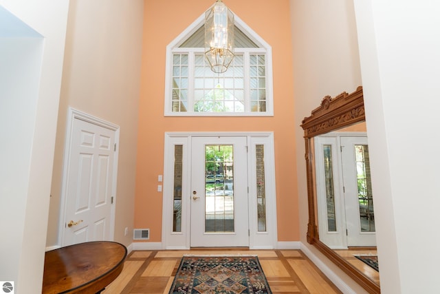 foyer entrance featuring a high ceiling, a chandelier, and baseboards