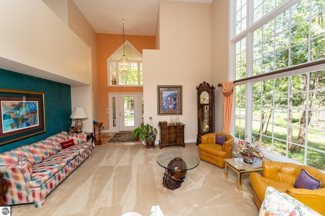 living room featuring a towering ceiling, plenty of natural light, baseboards, and carpet